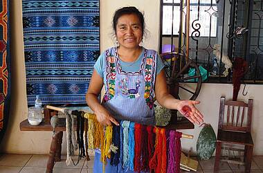 Frau in tradioneller bunter Kleidung präsentiert gefärbte Fasern, Kunsthandwerk Oaxaca