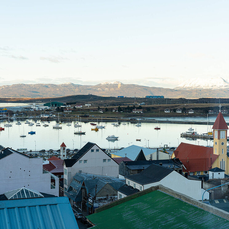 Ausblick vom Hotel Alto Andino in Ushuaia, Argentinien, auf den Beagle-Kanal mit Segelbooten, farbigen Dächern und den Bergen Feuerlands im Hintergrund.
