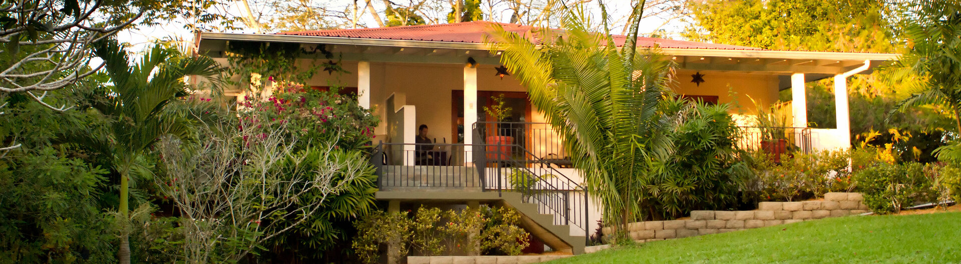 Hauptgebäude des Ka'ana Resort in San Ignacio, Belize inmitten gepflegter Gartenanlage mit überdachter Veranda.