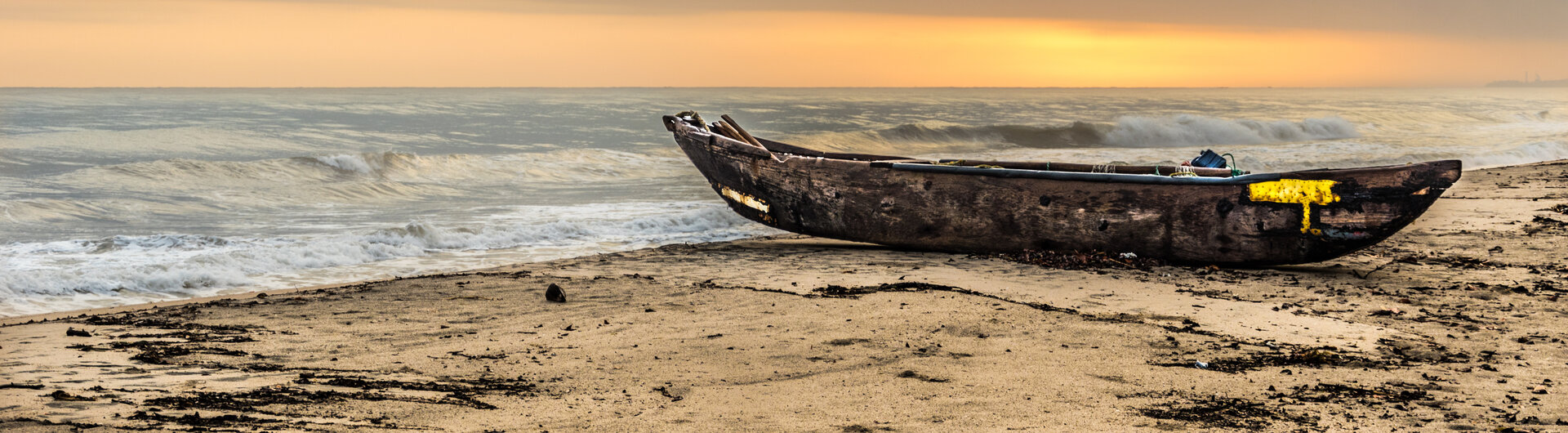 Ein hölzernes Fischerboot am Sandstrand bei Sonnenuntergang im Tayrona-Nationalpark in Kolumbien.