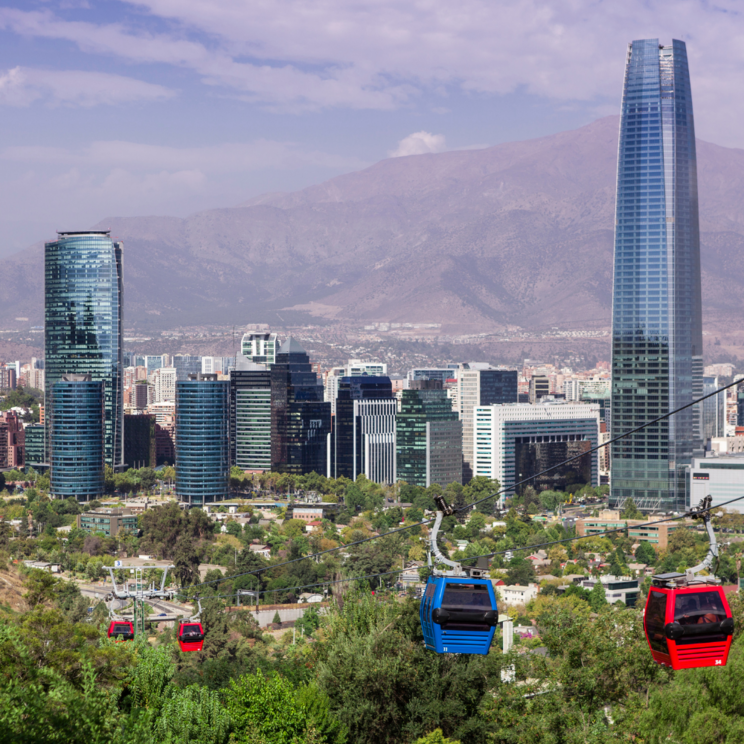 Panoramablick auf Santiago de Chile mit moderner Skyline, Seilbahn im Parque Metropolitano und den Anden im Hintergrund.