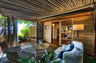 Überdachte Terrasse mit Sitzecke, Sofa und Holzhütten-Architektur in Mancora, Peru.