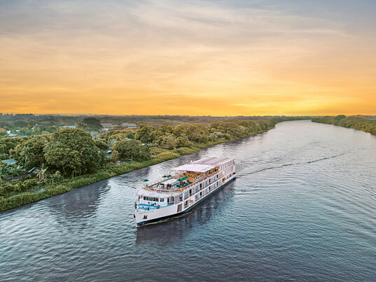 Das Flusskreuzfahrtschiff AmaMagdalena gleitet bei goldenem Abendlicht auf dem ruhigen Magdalena-Fluss, umgeben von dichtem Grün