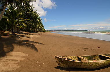 Strand mit Boot und Palmen an der Pazifikküste Kolumbiens