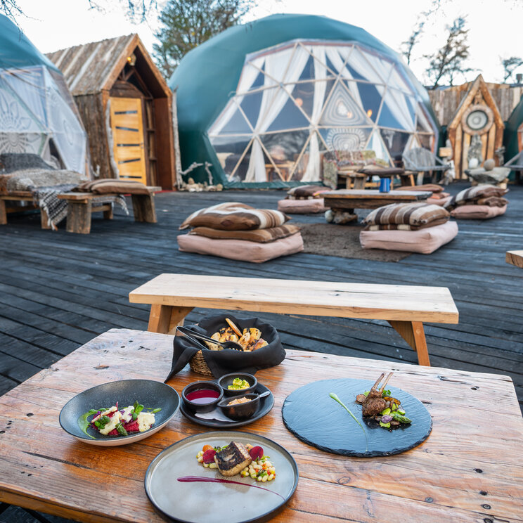Terrasse des EcoCamp Patagonia im Torres del Paine Nationalpark mit gedecktem Tisch und geodätischen Domzelten im Hintergrund.