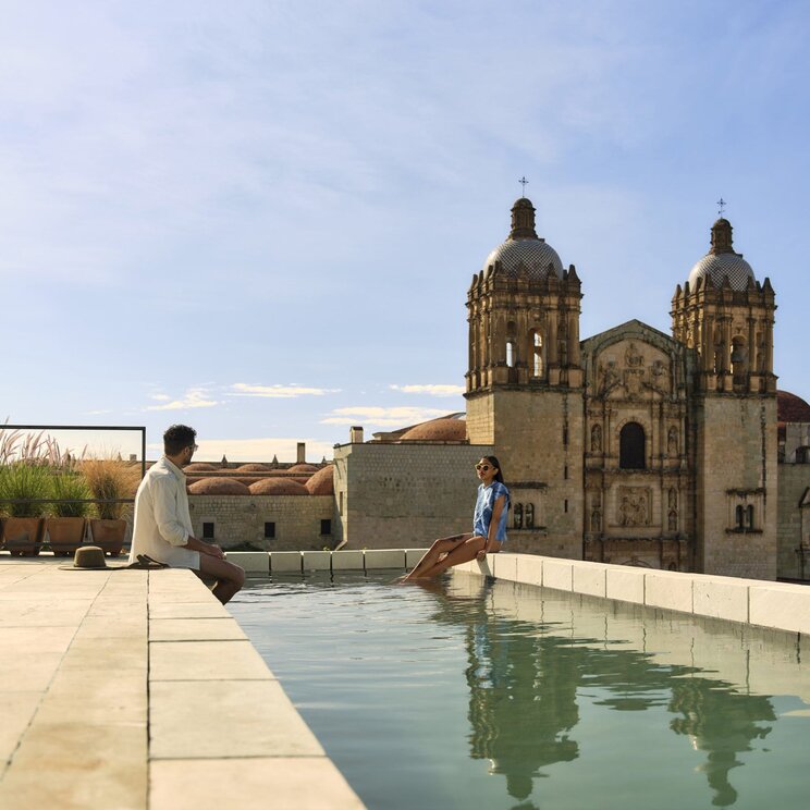 Paar am Rooftop-Pool des Hotel Otro mit Blick auf die Kathedrale Santo Domingo in Oaxaca, Mexiko.