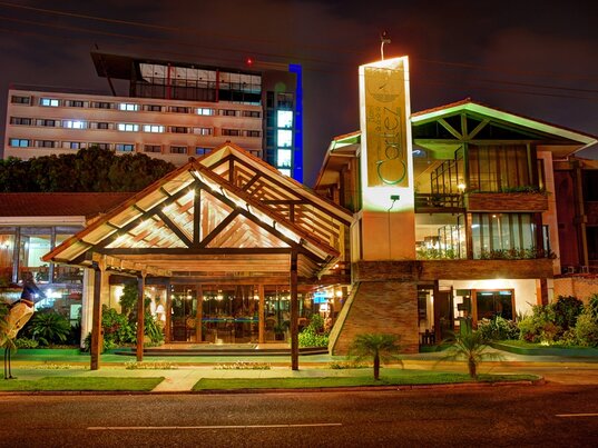 Beleuchtete Außenansicht des Hotel Cortez in Santa Cruz bei Nacht mit hölzernem Eingangsbereich.
