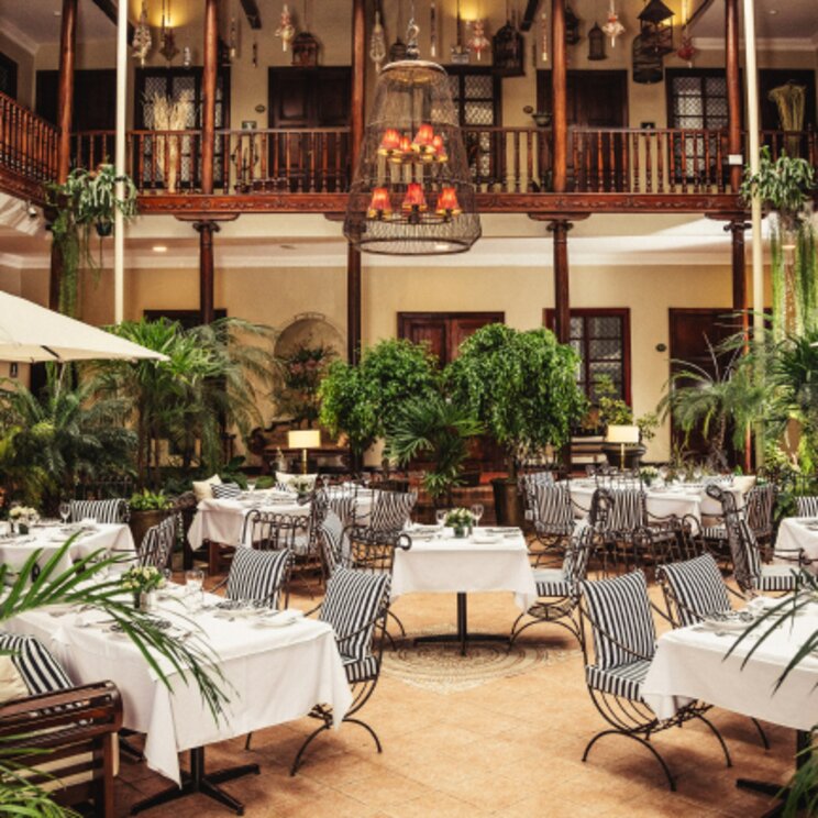 Restaurant im Innenhof des Hotel Santa Lucia in Cuenca, Ecuador mit stilvoll gedeckten Tischen, üppiger Bepflanzung und kolonialem Ambiente.