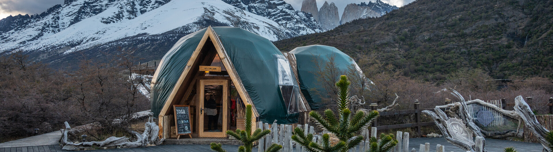 Aussenansicht des Welcome Domes mit Eingangstuer und Bergpanorama bei Daemmerung in Torres del Paine, Chile.