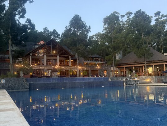 Großzügige Poolanlage und stimmungsvoll beleuchtetes Hauptgebäude des Carmelo Resort & Spa, umgeben von Eukalyptus- und Kiefernwäldern in Carmelo, Uruguay