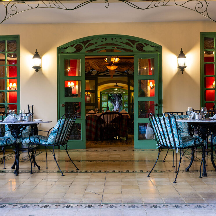 Terrasse des Hotel Casa Turire bei Turrialba, Costa Rica, mit elegant gedeckten Tischen, schmiedeeisernen Möbeln und Zugang zum stilvollen Innenbereich.