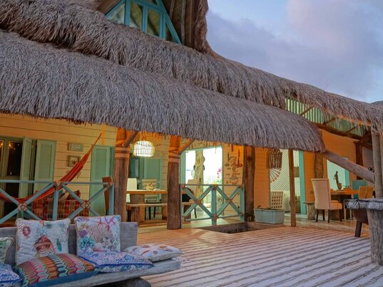 Außenbereich der Golden Sea Casa Boutique auf Providencia bei Abendlicht mit Strohdach, bunter Einrichtung und gemütlicher Terrasse – charmantes Hotel auf der kolumbianischen Karibikinsel mit entspannter Atmosphäre.