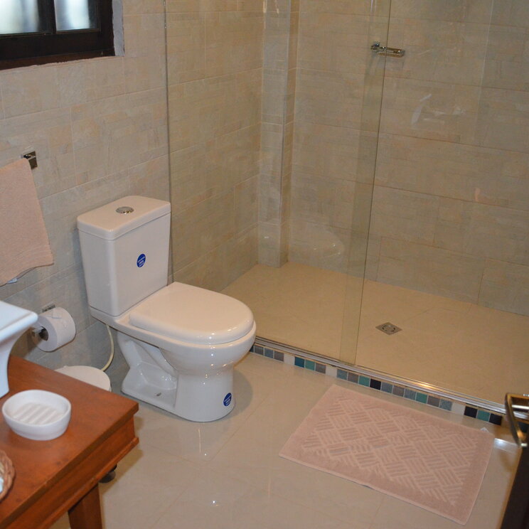 Modernes Badezimmer im Hotel Monasterio mit ebenerdiger Glasdusche und hellem Fliesenspiegel in Kolumbien.