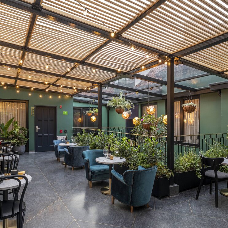 Terrasse im HAB Hotel Bogotá mit gemütlichen Sitzbereichen, viel Grün und stimmungsvoller Beleuchtung