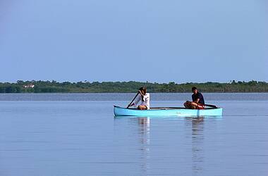 Eine junge Frau und ein junger Mann fahren Kanu auf einem Fluss in Belize