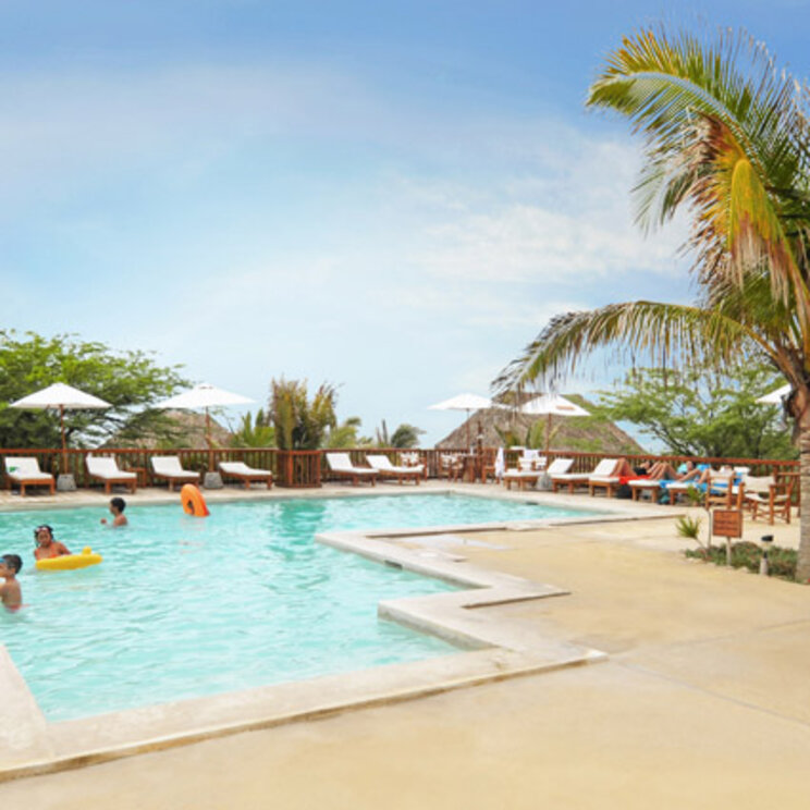 Aranwa: Hotelgäste entspannen im und am Pool mit Liegen, Sonnenschirmen und Palmen.