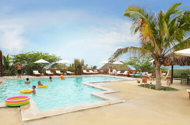 Aranwa: Hotelgäste entspannen im und am Pool mit Liegen, Sonnenschirmen und Palmen.