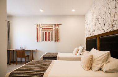 Modernes Zweibettzimmer mit gewebtem Wandteppich und schwarz-weiss gemusterter Tapete in San Pedro de Atacama.