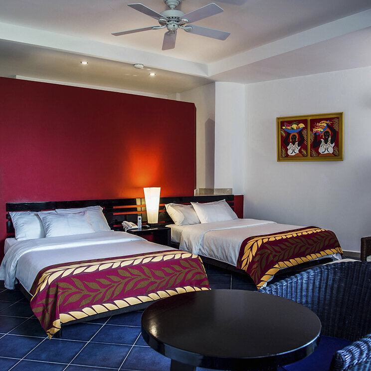 Hotelzimmer mit zwei Betten, einer roten Wand und blauen Bodenfliesen auf der Insel Barú.