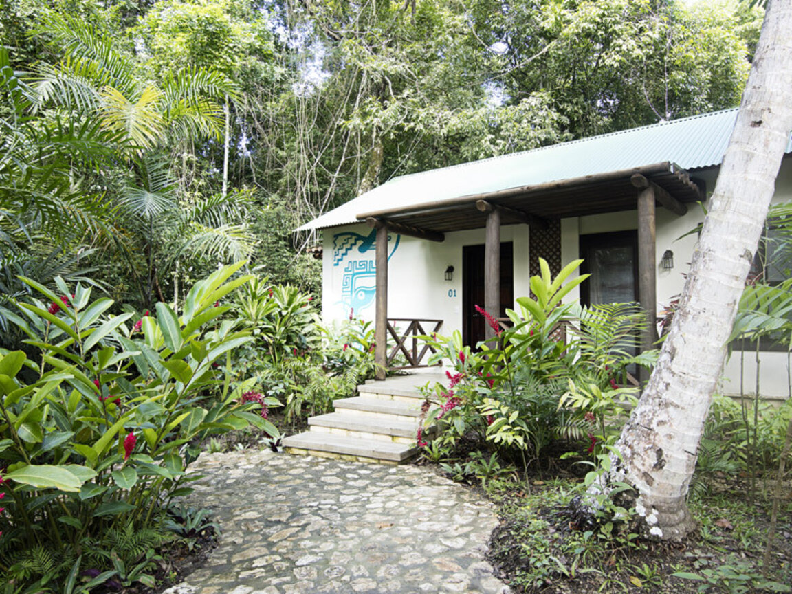 Idyllisches Bungalow-Gebäude der Suite Ortiz in der Jungle Lodge Tikal, eingebettet in eine üppige tropische Gartenanlage nahe Flores, Guatemala