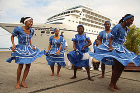 Tänzerinnen in blauen Kleidern begrüßen Ankömmlinge am Lago Izabal, Guatemala