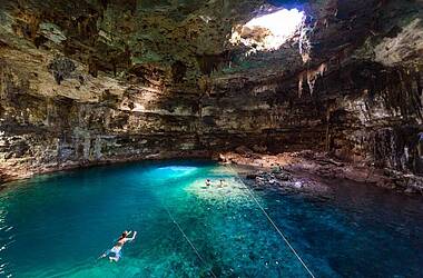 Leute schwimmen im türkisen Wasser einer Cenote in Mexiko