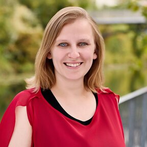 Judith Seeck, Mitarbeiterin bei Gateway Lateinamerika, steht lächelnd auf einer Brücke mit grünem Flussufer im Hintergrund.