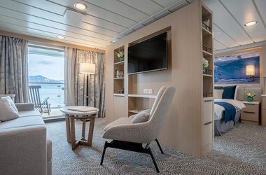 Die geräumige Suite auf der Ocean Albatros mit Wohnbereich, modernem Design und privatem Balkon mit Meerblick