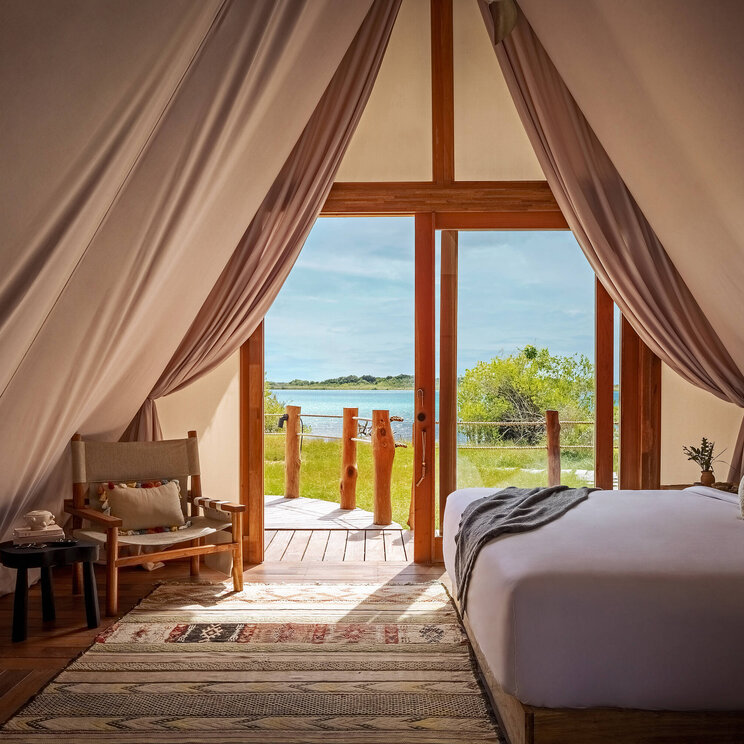 Zelt-Suite im Hotel Our Habitas Bacalar mit gemütlicher Einrichtung und Blick auf die Lagune.