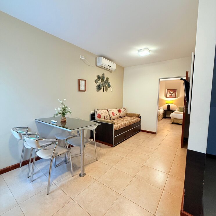 Wohnbereich mit Esstisch, Sofa, Klimaanlage und Blick ins angrenzende Schlafzimmer einer Lodge in Iguazu.