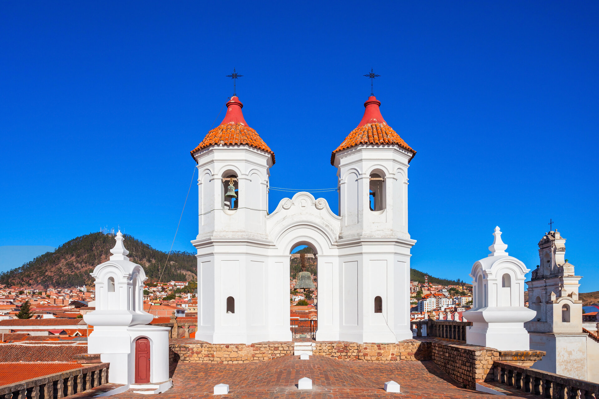 Kathedrale von Sucre in Bolivien mit weißen Türmen und orangefarbenen Kuppeln über der kolonialen Altstadt vor blauem Himmel.
