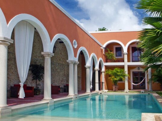 Aussenpool im Innenhof der Hacienda Merida mit Rundboegen, Saeulen und Palmen in Mexiko.