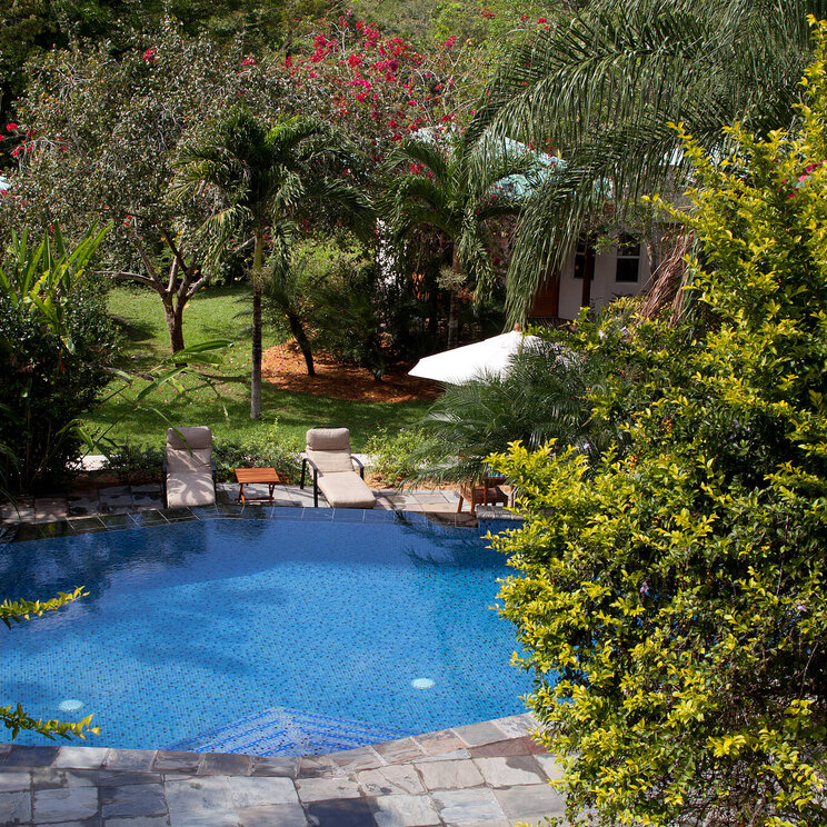 Runder Pool im Ka'ana Resort in San Ignacio, Belize, umgeben von Liegestühlen, Palmen und tropischer Gartenlandschaft.
