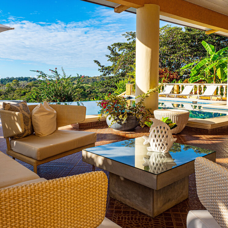 Sonnige Hotelterrasse mit Lounge-Möbeln und Blick auf den Infinity-Pool und den Dschungel Panamas.