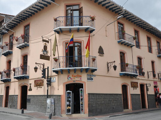 Außenansicht des Hotel Los Balcones in Cuenca, Ecuador, mit rosafarbener Kolonialfassade, schmiedeeisernen Balkonen und zentraler Lage an einer Straßenecke der Altstadt.