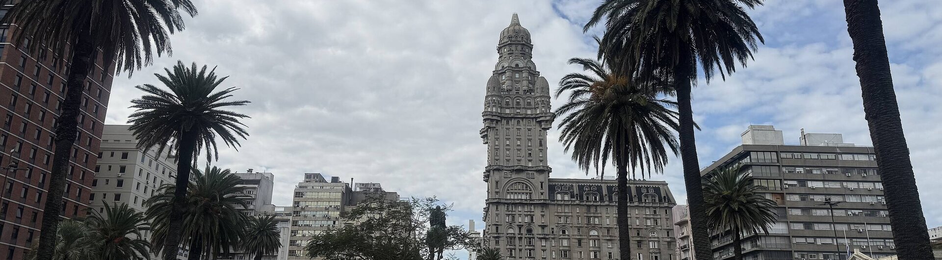 Der Palacio Salvo steht auf der Plaza Independencia in Montevideo, umgeben von Palmen und einem Park