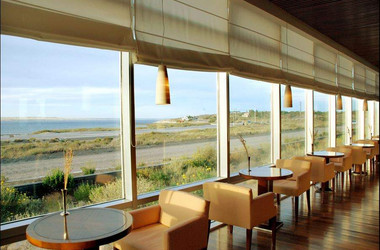 Tische und Stühle vor einem Panoramafenster im Hotel Territorio in Puerto Madryn