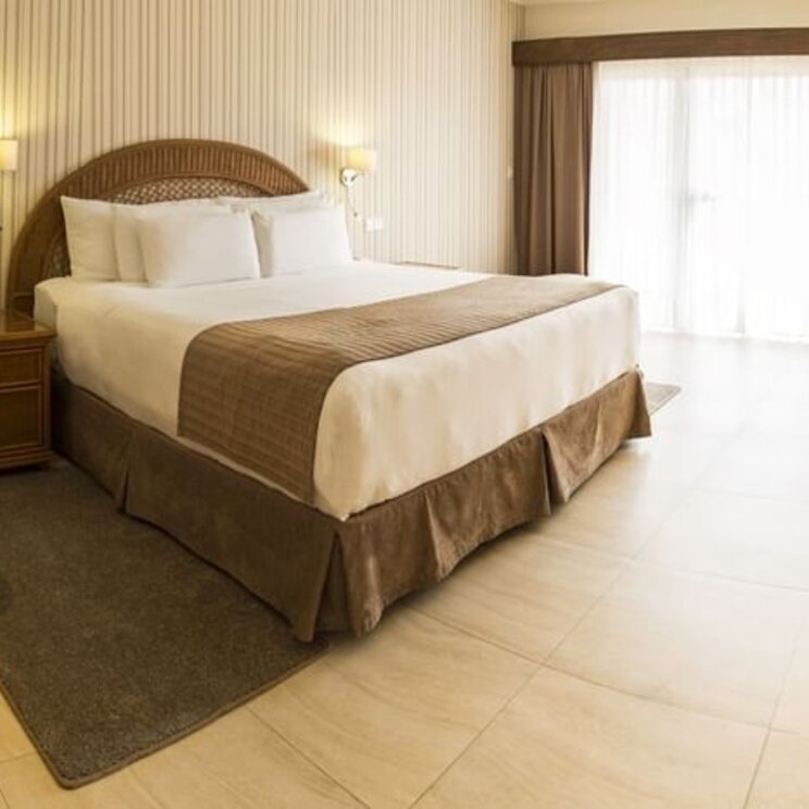Helles Schlafzimmer der Royal Suite im Camino Real Hotel Santa Cruz mit Kingsize-Bett und gestreifter Tapete.
