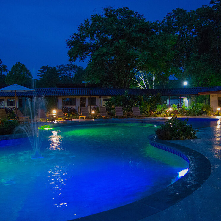 Restaurant im La Foresta Nature Resort in Manuel Antonio, Costa Rica, mit Blick auf den Poolbereich und stimmungsvoller Abendbeleuchtung.