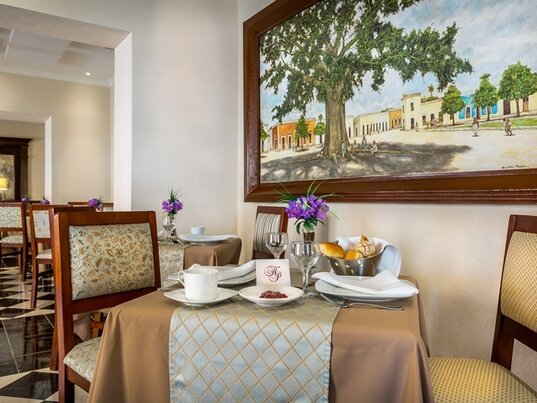 Gedeckter Fruehstueckstisch im Hotelrestaurant mit Gemaelde und Schachbrettboden in Campeche.