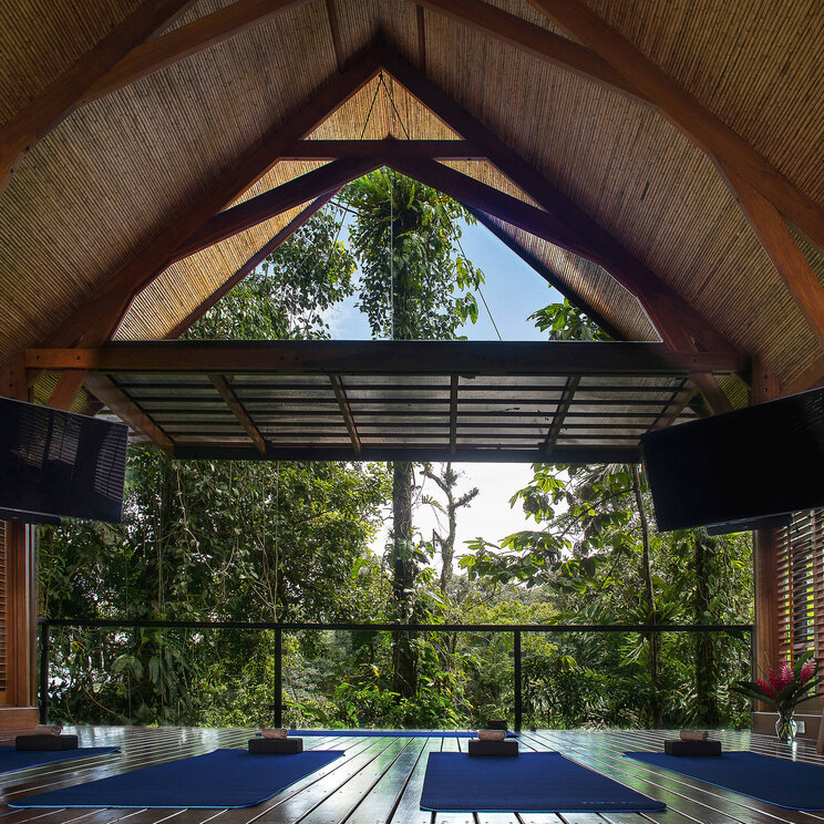 Offenes Yoga-Studio im Hotel Amor Arenal in La Fortuna, Costa Rica, mit Holzstruktur, Blick in den Regenwald und entspannter Atmosphäre für Fitness und Meditation.