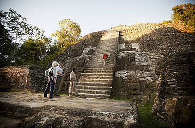 Eine Person klettert auf eine Pyramide in der Mayastätte Lamanai in Belize