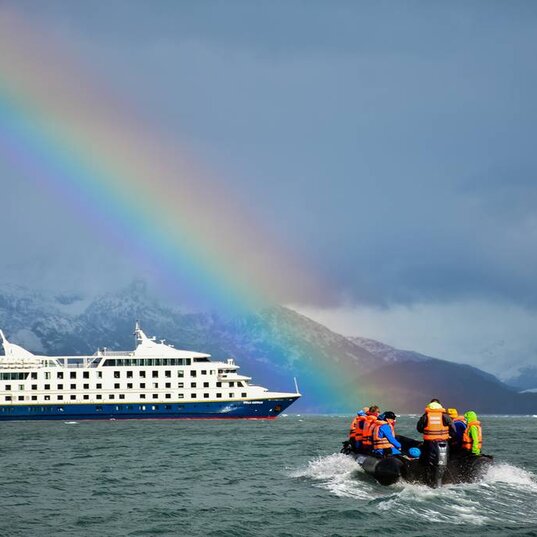Cruceros Australis Schiff und Zodiak mit Regenbogen im Hintergrund
