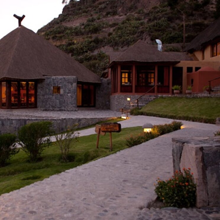 Außenansicht der erleuchteten Colca Lodge Spa & Hot Springs bei Dämmerung, Colca Canyon Peru 