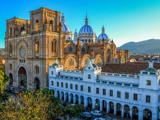 Die imposante Backsteinfassade der Kathedrale von Cuenca (Catedral de la Inmaculada Concepción) mit ihren typischen Kuppeln unter leicht bewölktem Himmel.