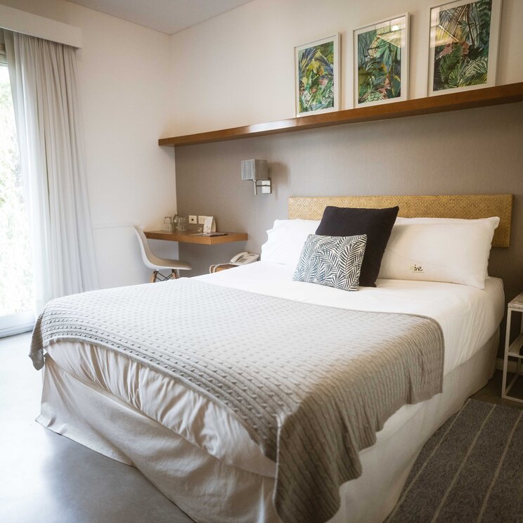 Hell eingerichtetes Doppelzimmer im Mine Hotel in Buenos Aires mit Doppelbett, Schreibtisch und Balkontuer.