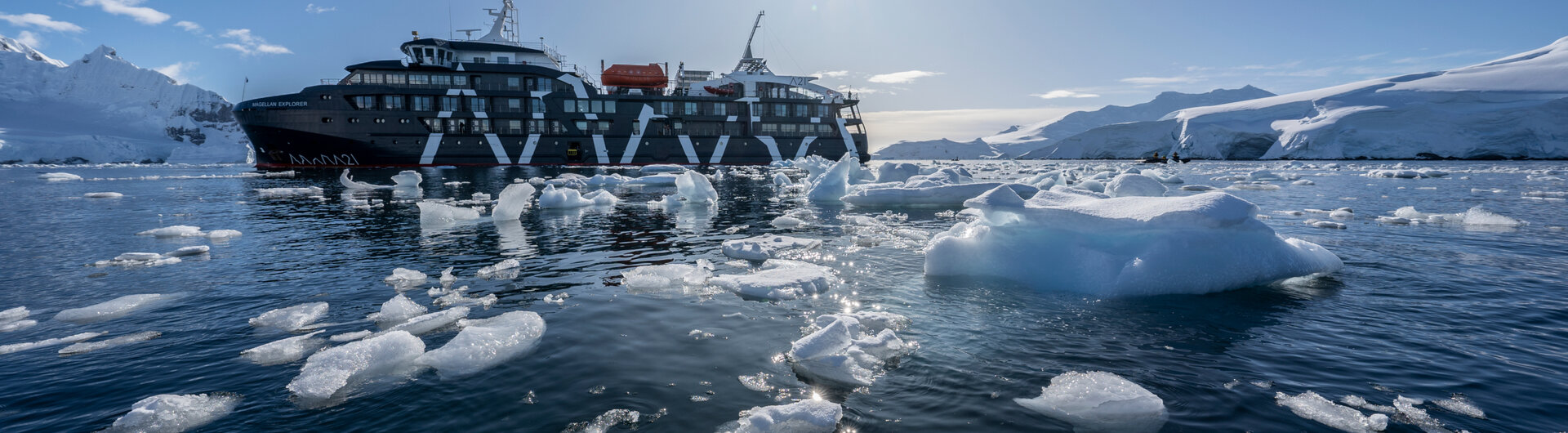 Expeditionsschiff Magellan Explorer in der Antarktis im Treibeis unter strahlender Sonne und blauem Himmel.