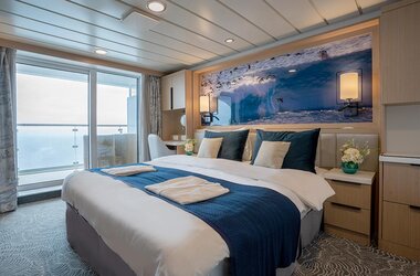 Heller und großzügiger French Balcony Stateroom auf dem Kreuzfahrtschiff Ocean Albatros mit Balkon, elegantem Design und Antarktispanorama an der Wand