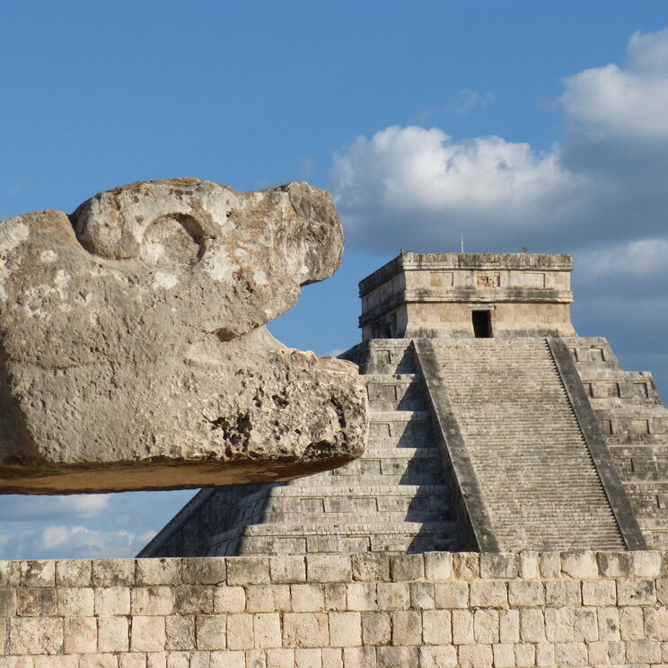 Schlangenkopf mit Kukulkan-Pyramide im Hintergrund in Chichen Itza - Mexiko