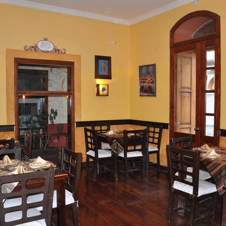 Frühstücksraum im Hotel Santa Isabella in Riobamba, Ecuador, mit Holzmöbeln, warmer Wandfarbe und traditioneller Dekoration.